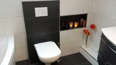 Vorwand-WC mit dunklen Fliesen und beleuchteter Nische