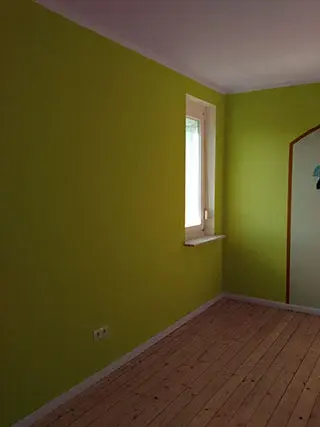 Frisch grün gestrichenes Zimmer mit Holzdielen