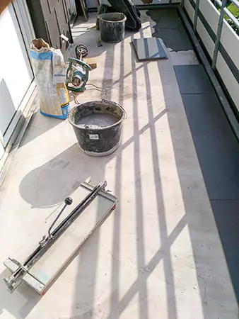 Balkon während der Verlegung mit Fliesenkleber und Werkzeug
